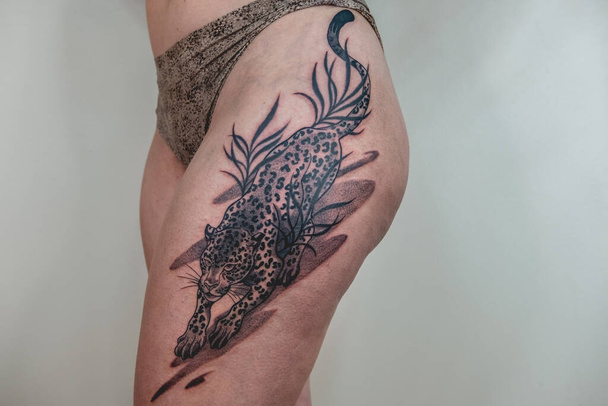Belle femme avec un gros tatouage terminé d'un tigre dans la cuisse et les hanches après la séance de tatouage - Photo, image