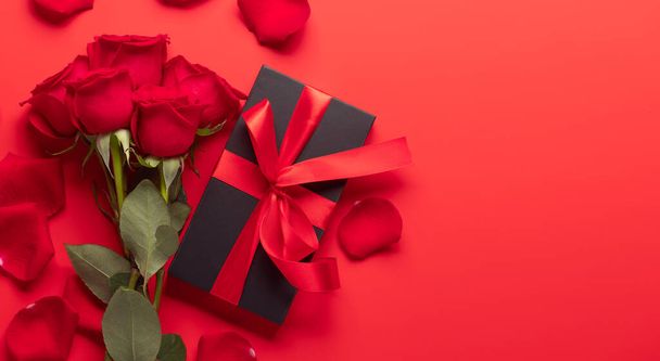 Valentines day card with gift box and rose flowers. On red background with space for your greetings - Photo, Image