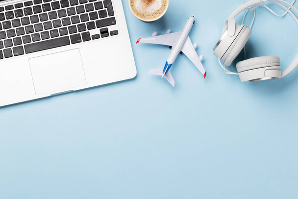 Travel and online booking concept. Laptop and airplane on blue desk with copy space - Foto, Imagen