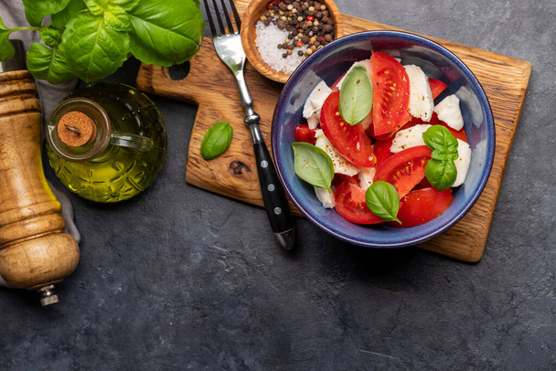 Салат капрезе с спелыми помидорами, сыром моцарелла и садовым базиликом. Квартира с копировальным пространством - Фото, изображение