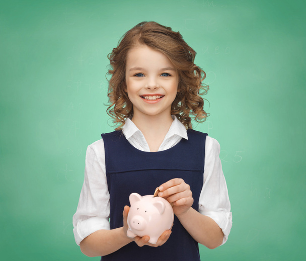 smiling girl putting coin into piggy bank - Foto, afbeelding