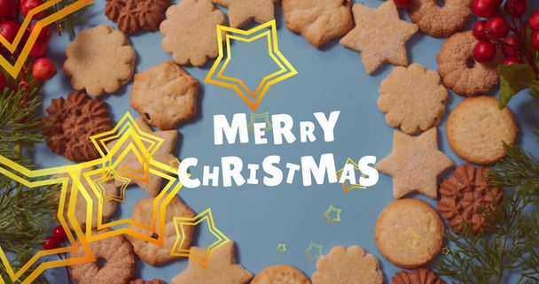 Merry christmas text banner and golden star icons floating against cookies on blue surface. christmas festivity and celebration concept - Photo, image