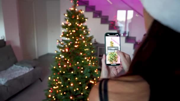 Bella donna che utilizza l'app Smart Home per decorare e illuminare l'albero di Natale. Vista posteriore. - Filmati, video