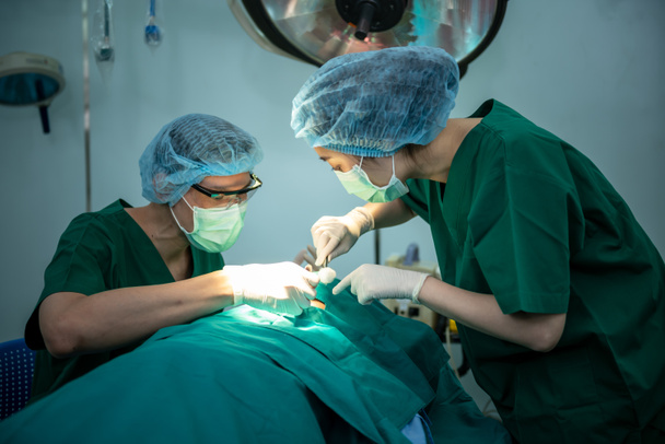 Asian medical team men and women working in the operating room, Doing nose surgery on a female patients. to people health care and cosmetic surgery concept. - Photo, Image