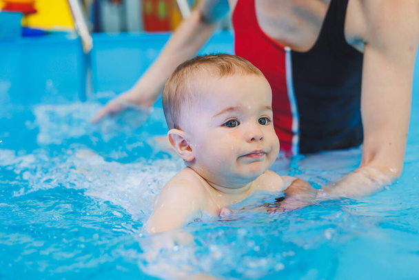Nauczyciel pływania uczy małego chłopca pływać w basenie. Pierwsze lekcje pływania dla dzieci. Rozwój niemowląt - Zdjęcie, obraz