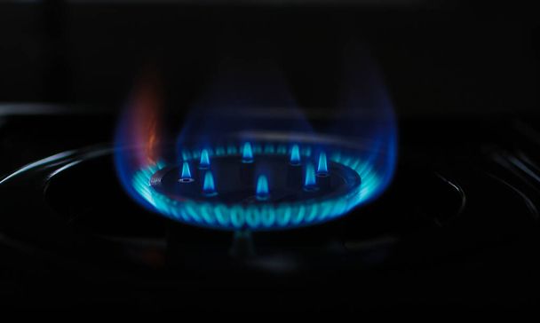 Mutfak ocağında koyu arkaplanda doğal gaz mavi alev. Dairesel gaz jeti. Alev Gazı Operasyonu. Kısıtlama ve kriz - Fotoğraf, Görsel