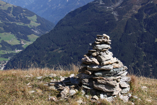 gran cairn de piedra en las montañas con una vista lejana del valle verde debajo - Foto, imagen