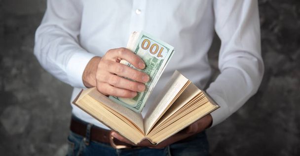man hand money on book on dark background - Φωτογραφία, εικόνα