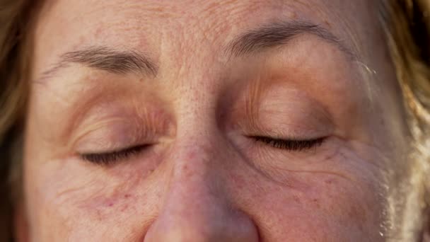Mujer mayor arrugada cerrando los ojos en meditación y contemplación. Macro primer plano de una mujer mayor con los ojos cerrados - Metraje, vídeo