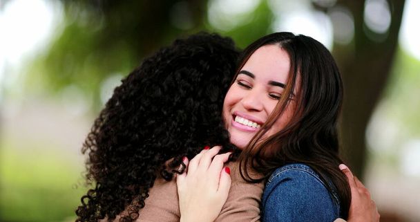 Dos chicas diversas abrazándose. Las mujeres jóvenes abrazan al aire libre - Foto, imagen