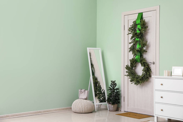 Interior de la sala con puerta de madera, coronas de Navidad y espejo - Foto, Imagen