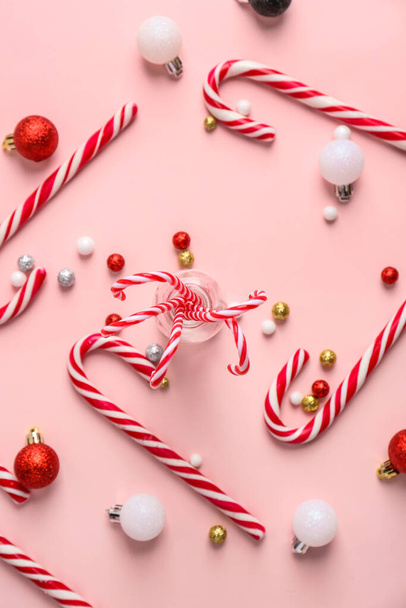 Composition with tasty candy canes and Christmas balls on pink background - Foto, Bild