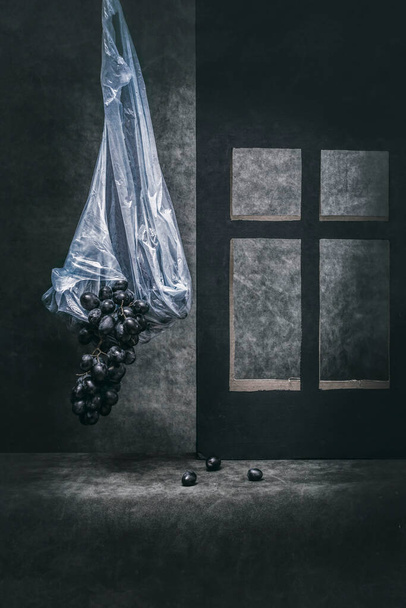 Martwa natura z ciemnymi winogronami w torbie przy oknie - Zdjęcie, obraz