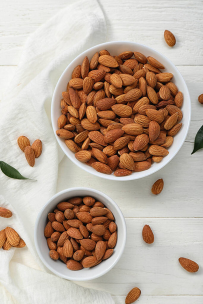 Bowls of almonds on white wooden table - Foto, Bild