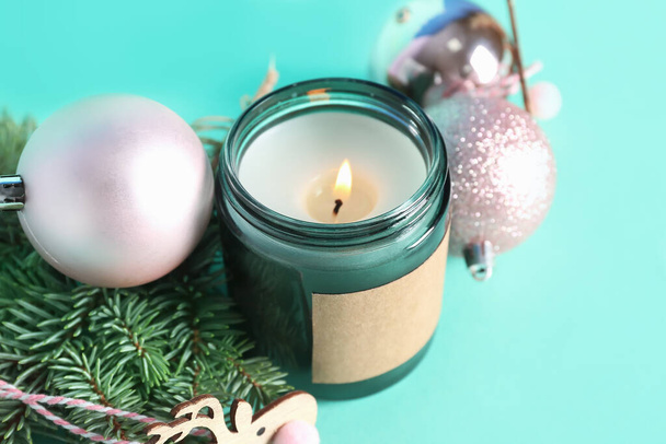 Jar with burning candle, Christmas toys and fir branches on color background, closeup - Foto, imagen
