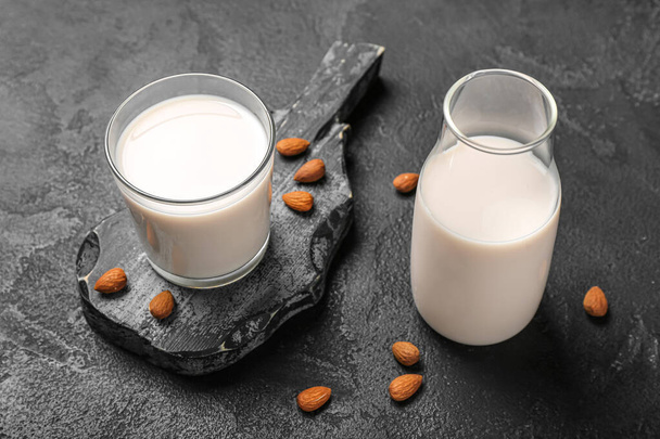 Дошка зі склом і пляшкою мигдалевого молока на темному фоні
 - Фото, зображення