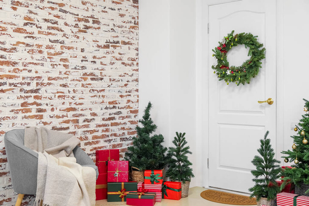 Porte blanche avec couronne de Noël, sapins et cadeaux dans le hall - Photo, image