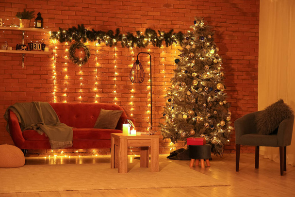 Interior of living room with Christmas tree, sofa and glowing lights at night - Valokuva, kuva