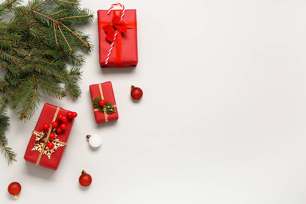 Χριστουγεννιάτικα κουτιά δώρου με κλαδιά ελάτης και μπάλες στο φως φόντο - Φωτογραφία, εικόνα