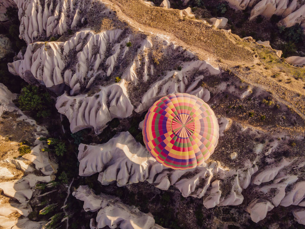 Colorful hot air balloons flying over at fairy chimneys valley in Nevsehir, Goreme, Cappadocia Turkey. Spectacular panoramic drone view of the underground city and ballooning tourism. High quality. - Fotoğraf, Görsel