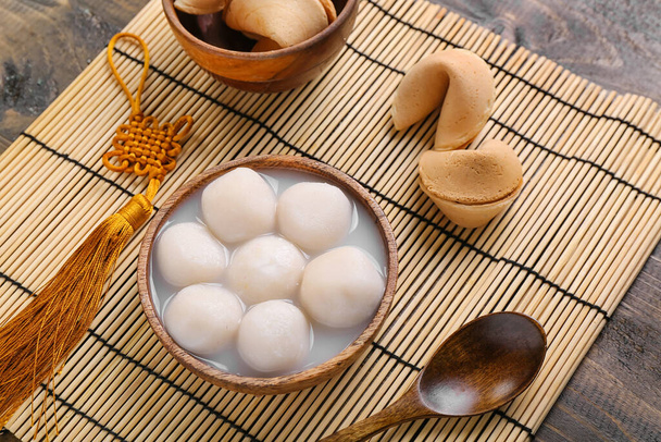 Mata bambusowa z miską tangyuan i ciasteczka z wróżbą na drewnianym tle. Festiwal Dongzhi - Zdjęcie, obraz