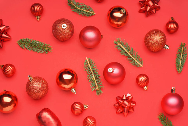 Kerstballen met sparren takken op rode achtergrond - Foto, afbeelding