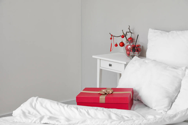 Jarrón con ramas de árbol, bolas de Navidad y difusor de caña en la mesa en el dormitorio - Foto, Imagen