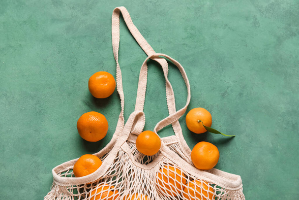 Shopping string bag with ripe tangerines on color background - Fotografie, Obrázek