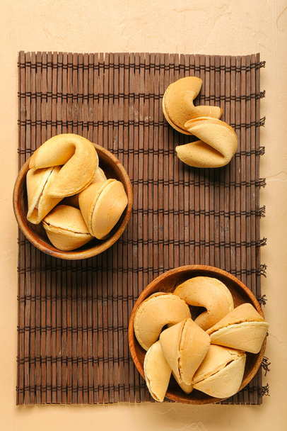 Estera de bambú con cuencos de galletas de la fortuna sobre fondo beige - Foto, imagen