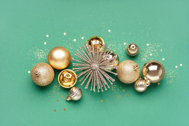 Golden Christmas balls with glitter on green background - Foto, Imagen