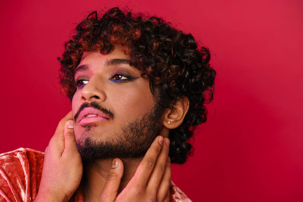 Young curly man with makeup posing and looking aside isolated over pink background - Fotografie, Obrázek