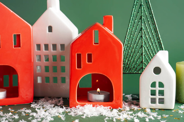 House shaped candle holders with snow on green background - Photo, Image