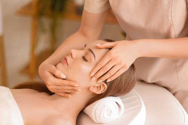mooie jonge vrouw ontvangst gezicht massage in schoonheid salon - Foto, afbeelding
