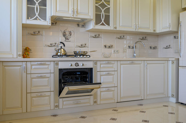 Klassiek wit en beige keukenmeubilair met oven open in studio appartement - Foto, afbeelding