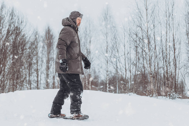 Kış parkında kar kayağı yapan bir adam sağlıklı, sportif bir yaşam tarzına sahiptir. Kış ormanlarında dinlenir ve yürür. - Fotoğraf, Görsel