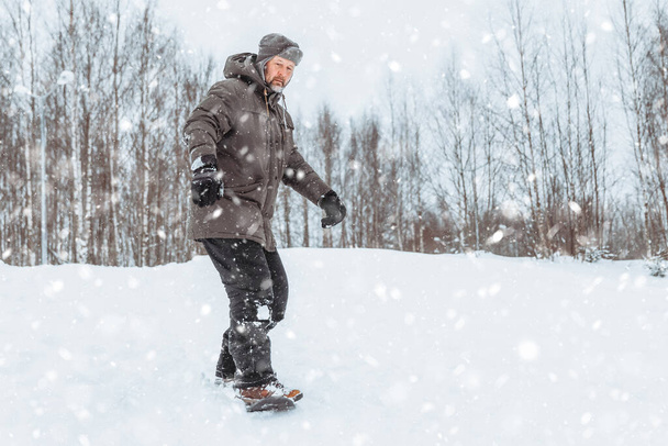Ein Mann fährt Schlittschuh im Winterpark, ein gesunder sportlicher Lebensstil, Erholung und Spaziergang in der Natur, im Winterwald - Foto, Bild