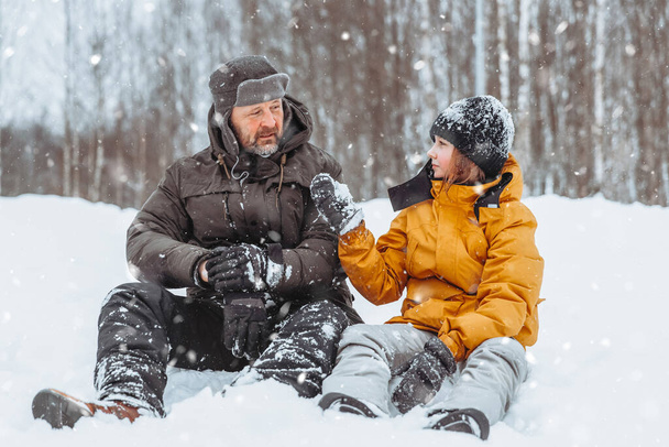 Vader en dochter wandelen door besneeuwd landschap, Familie wandeling in het winterpark. - Foto, afbeelding