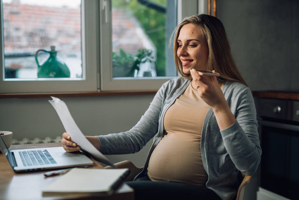 Pretty pregnant woman managing house finances - Valokuva, kuva