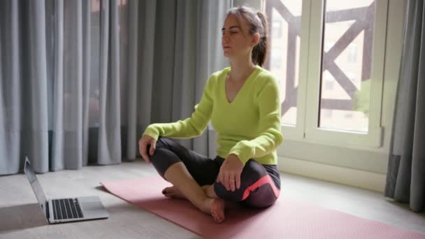 Junge brünette Frau in Sportbekleidung übt Meditation Atemzüge in Online-Video-Klasse. Hochwertiges 4k Filmmaterial - Filmmaterial, Video