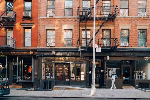 New York, USA - 21 novembre 2022: Fila di negozi su Elizabeth Street a Nolita, una zona affascinante e di lusso di Manhattan famosa per i suoi negozi e ristoranti, l'uomo cammina di fronte. - Foto, immagini