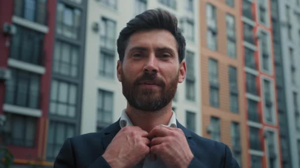 Stylový kavkazský podnikatel 30s muž vousatý profesionální muž podnikatel majitel podniku vůdce orgánu na sobě luxusní formální oblek zapínání košile stojící ve městě moderní mrakodrap pozadí - Záběry, video
