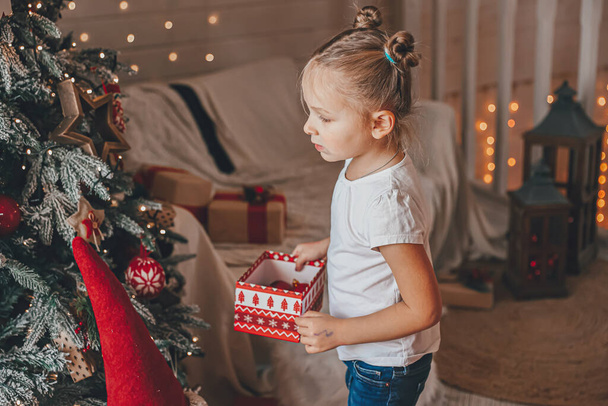 Cute little girl decorates a Christmas tree. Merry Christmas and New Year Holidays. - Foto, Imagem