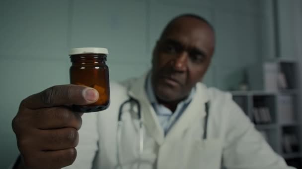 Medico maschio africano uomo maturo medico generico scienziato lavora in laboratorio leggere le istruzioni effetti collaterali sulla bottiglia medica con pillole antidroga vitamine integratore alimentare promozione di nuovi farmaci - Filmati, video