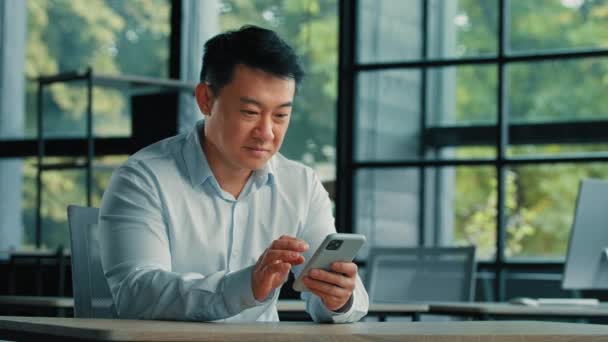Ενθουσιασμένος έκπληκτος νικητής επιχειρηματίας επιτυχημένη ώριμη ασιατική ιαπωνική κορεάτης Κινέζος κερδίζει έκπληξη κερδοφόρα προσφορά online στοιχημάτων ανάγνωση καλή ειδοποίηση στο κινητό τηλέφωνο χαίρονται επιχειρηματική επιτυχία - Πλάνα, βίντεο