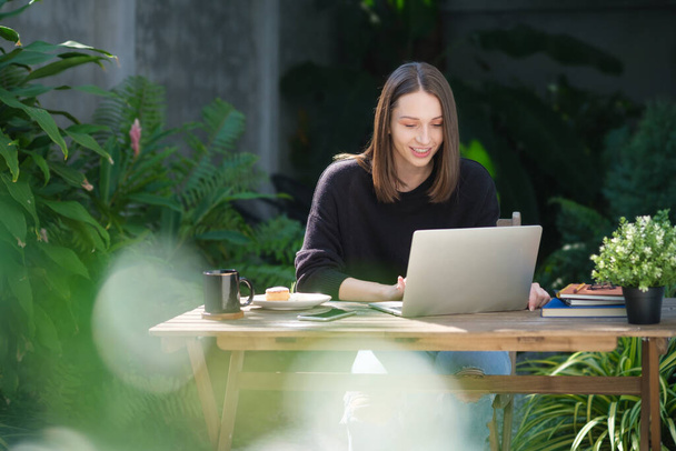 Shot of casual young woman sitting in the garden and using laptop while working from home. Home office.	 - Fotoğraf, Görsel