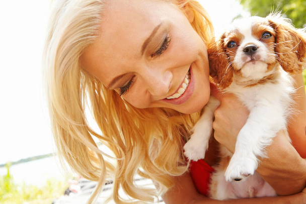 Puppys dag uit. een glimlachende, mooie blonde met haar puppy terwijl ze geniet van een dagje uit - Foto, afbeelding
