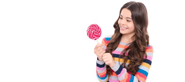 счастливая девушка-подросток в красочном свитере с леденец конфеты на палочке изолированы на белом фоне, магазин сладостей. - Фото, изображение