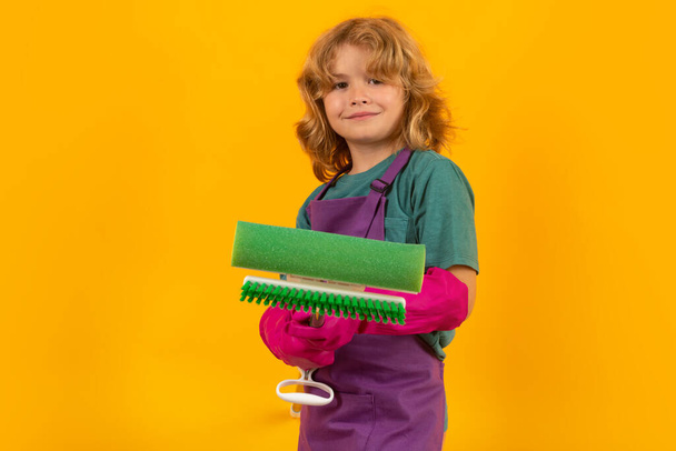 Dziecko robi prace domowe. Studio portret dziecka używać odkurzacz i rękawice do czyszczenia. Zabawna myjnia dla dzieci. Akcesoria do czyszczenia, środki czyszczące. Sprzątanie i sprzątanie domu - Zdjęcie, obraz