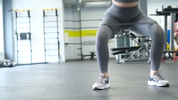 ビデオでは、女性は現代のジムでスクワットをし、足の筋肉を訓練します。総合的なフィットネストレーニング。健康な体の概念. - 映像、動画