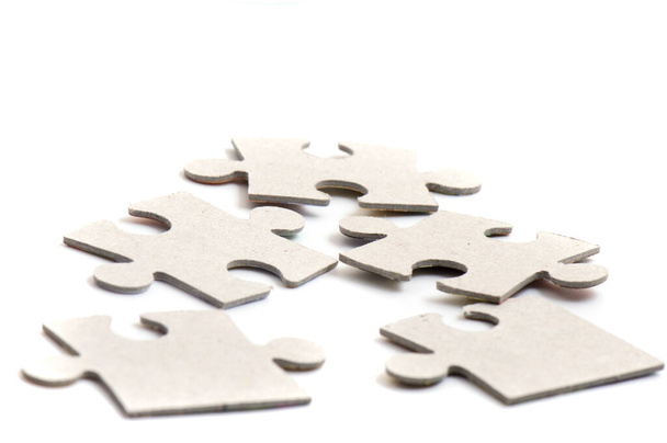 Close-up van puzzelstukjes, blanco wit papier legpuzzelelementen aan elkaar gekoppeld en gescheiden. - Foto, afbeelding